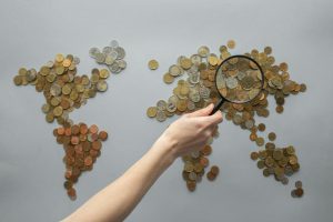 Searching through a world map made with coins.